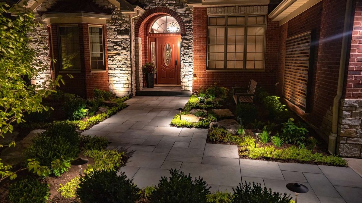 paver walkway to entrance of home lit with landscape lighting