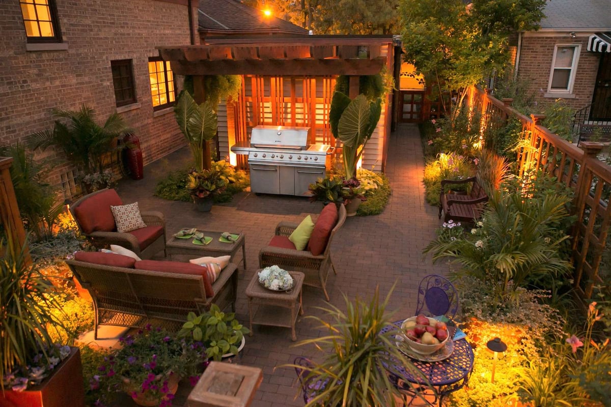 landscape lighting in backyard with patio and outdoor kitchen