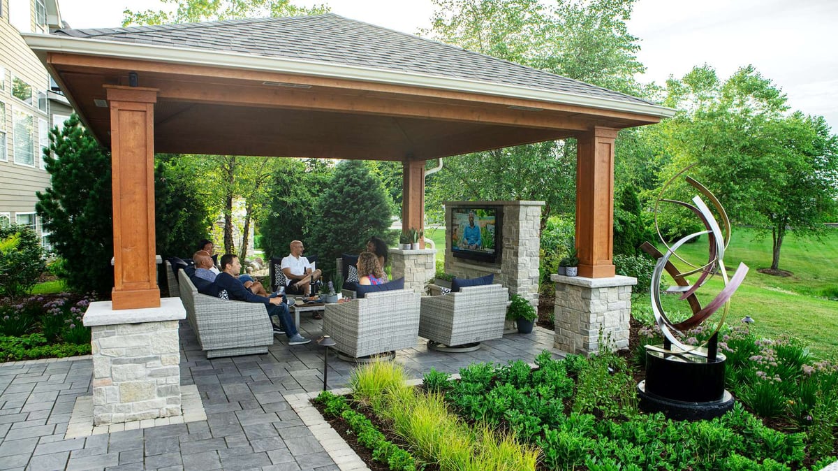family sits under pavilion around television