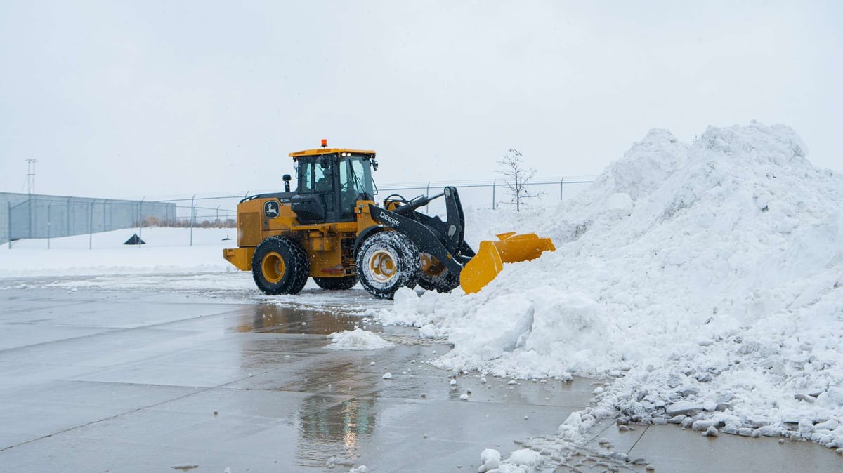 front loader piles snow in commercial parking lot