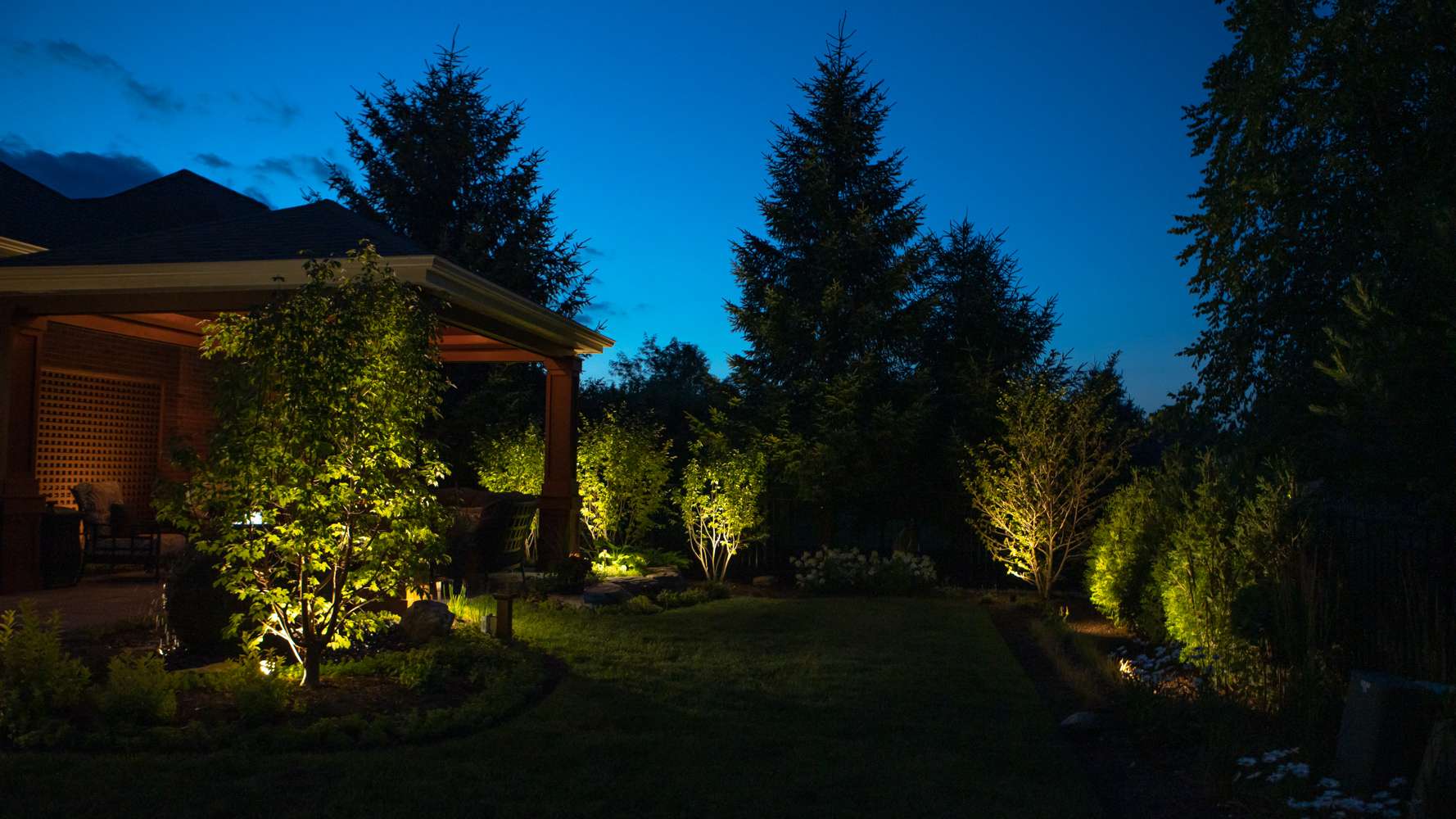 landscape lighting in backyard with trees and pavilion