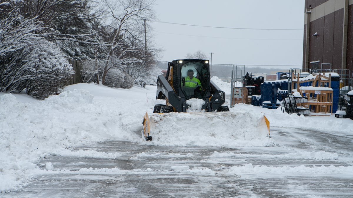 skid loader moves snow on commercial property