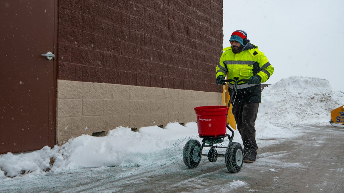 snow removal team salts sidewalk at commercial property